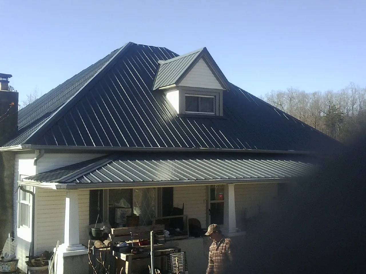 Dark blue standing seam metal roof with a dormer above a front porch in Niwot