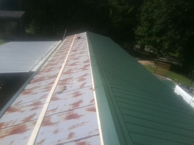 Old rusted panels beside newly installed green metal roofing — Wind Damage Roof Repair by Roofing Brothers in Niwot