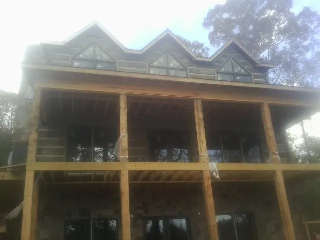 Dormers and porch framing on a large log home under construction — Roof Coating work by our crew in Niwot