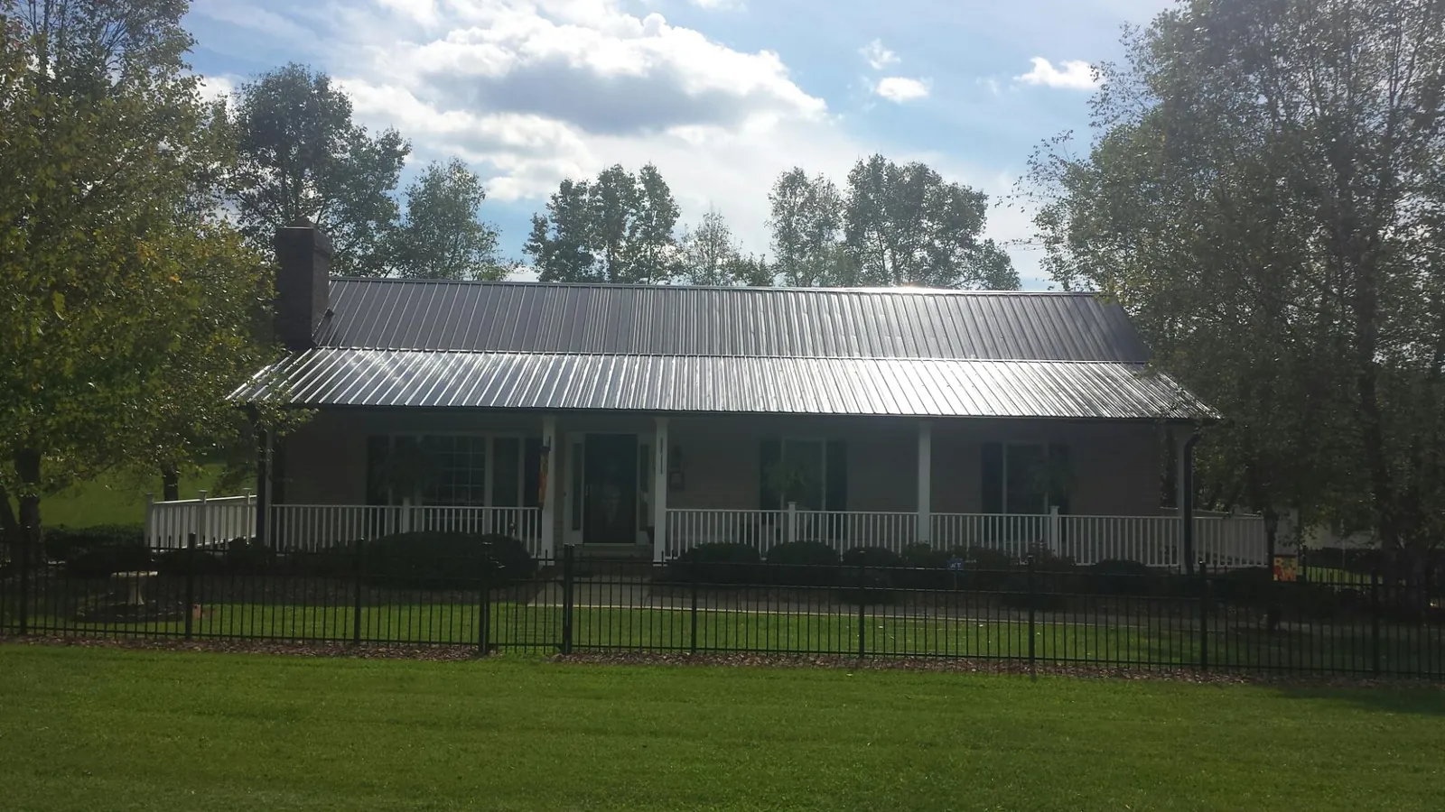 Gray metal roof on a brick ranch with a full width front porch — Gutter Guard Installation work by our crew in Niwot