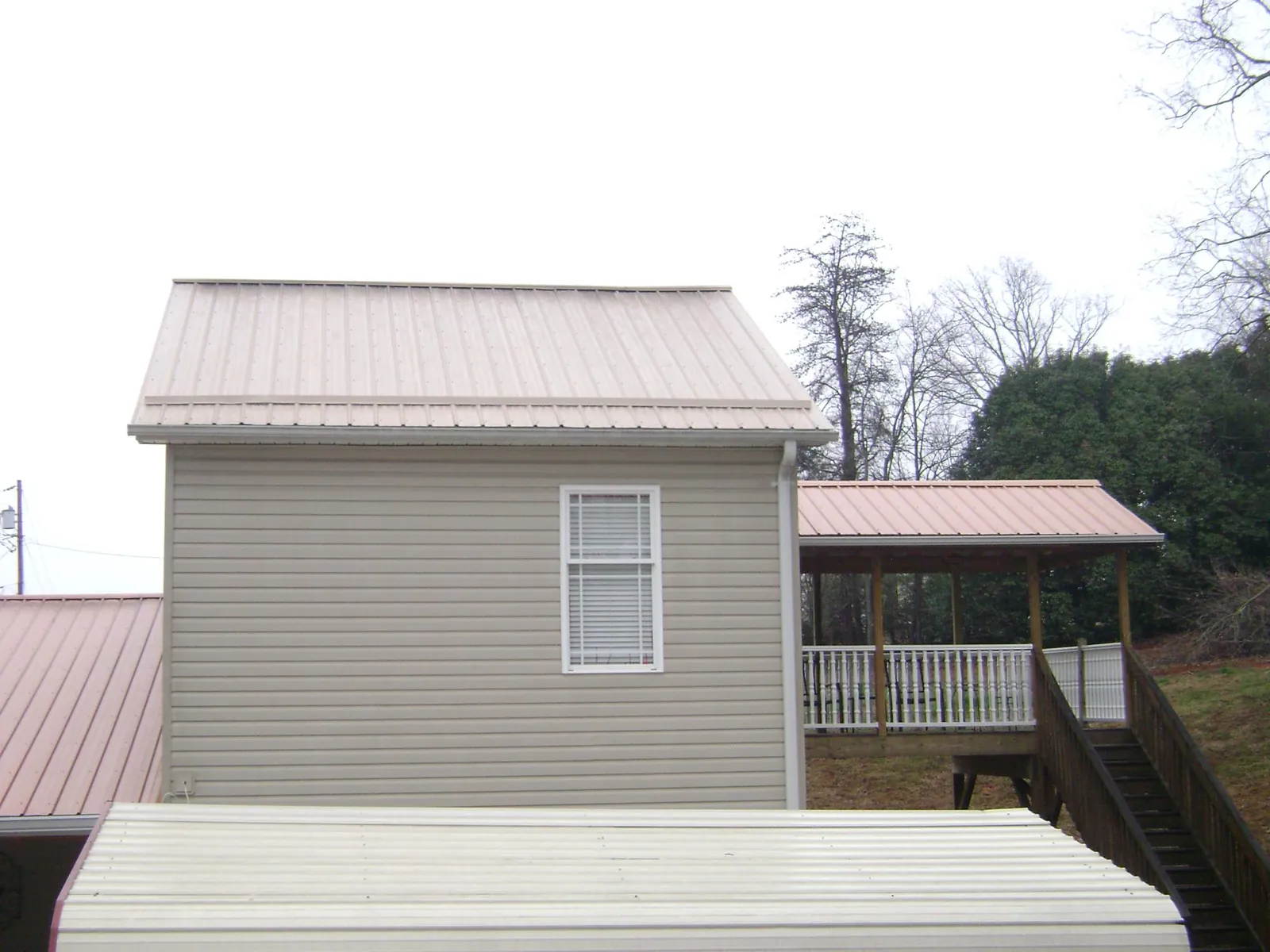 Tan metal roofs on a two story addition and attached porch, from a Roof Replacement job in Niwot