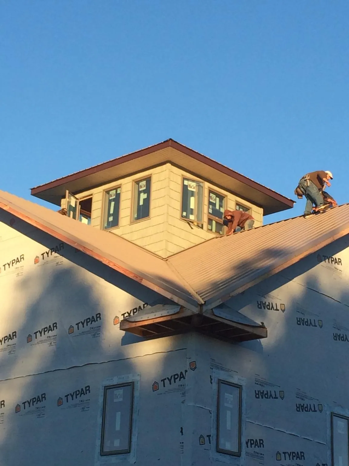Roofers working around a rooftop cupola on a new metal roof at sunset — Roof Waterproofing in Niwot by Roofing Brothers
